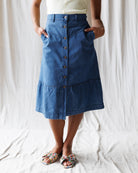 Person wearing a blue skirt with buttons on a white background