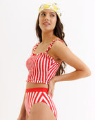 Woman wearing a red and white striped swimsuit with a matching headscarf on a white background