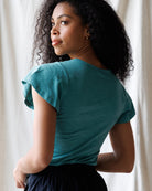 Woman wearing a teal top with a neutral background