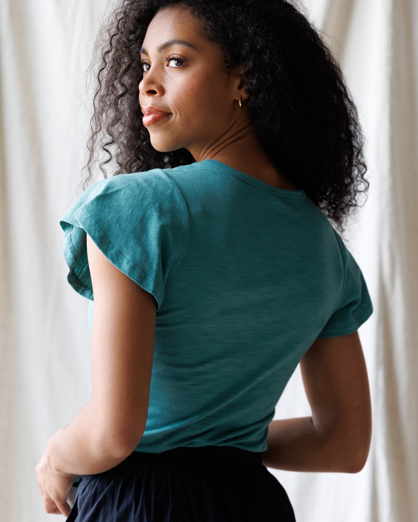 Woman wearing a teal top with a neutral background