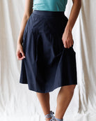 Person wearing a navy blue skirt with a white background