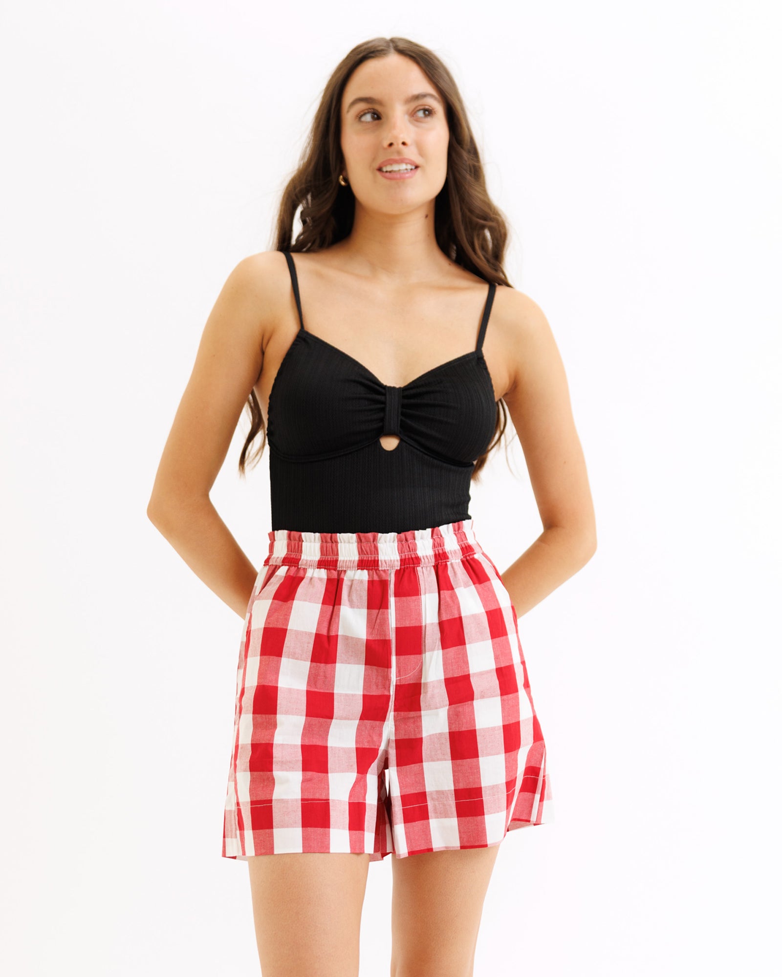 Woman wearing a black top and red checkered shorts on a white background