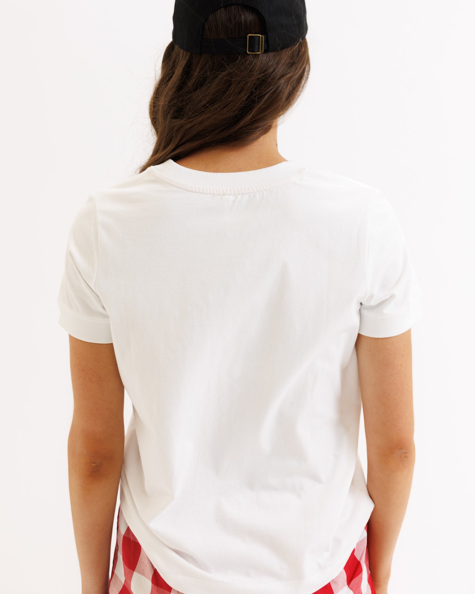 Person wearing a white t-shirt with a red and blue design on a plain background