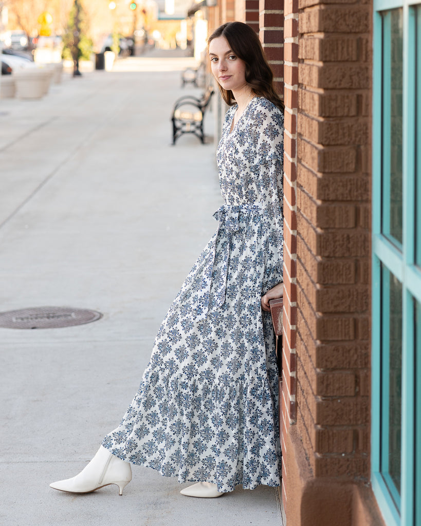 Model wearing a white and blue maxi length long sleeve dress.