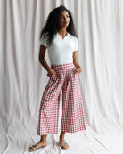 Woman wearing a white top and red checkered pants against a plain background
