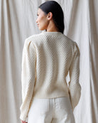 Person wearing a textured cream sweater against a neutral background