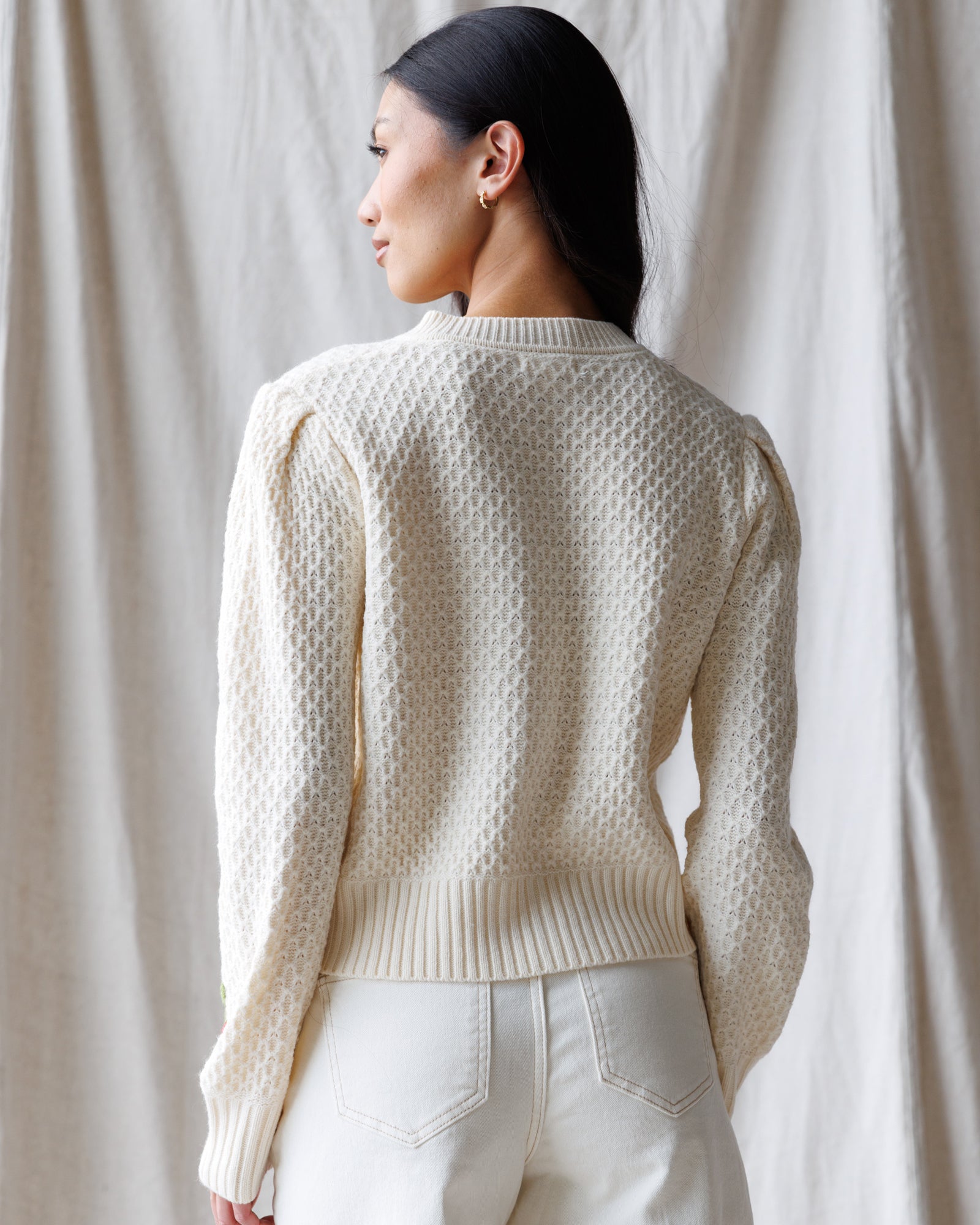 Person wearing a textured cream sweater against a neutral background