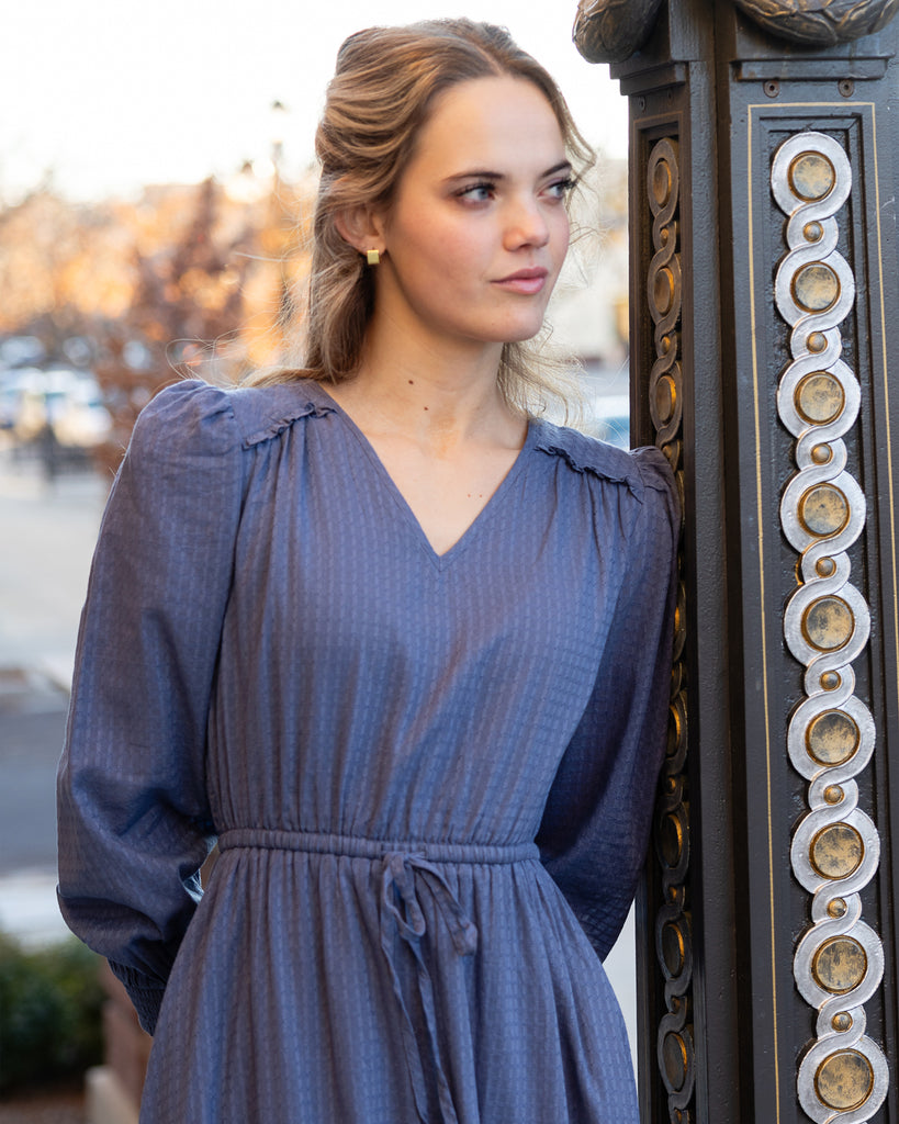 Model wearing a blue long sleeve, midi-length, v-neck dress.