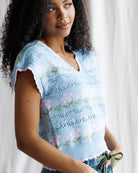 Woman wearing a light blue embroidered top against a white background