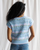Person wearing a light blue floral-patterned sweater against a white background