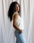 Woman wearing a striped shirt and jeans against a white curtain background
