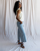 Woman wearing a striped shirt and light blue jeans against a white background
