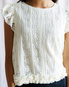 White lace top worn by a person on a white background