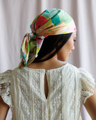 Woman wearing a colorful headscarf with a plain background