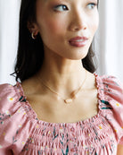 Woman wearing a pink floral dress with a delicate necklace