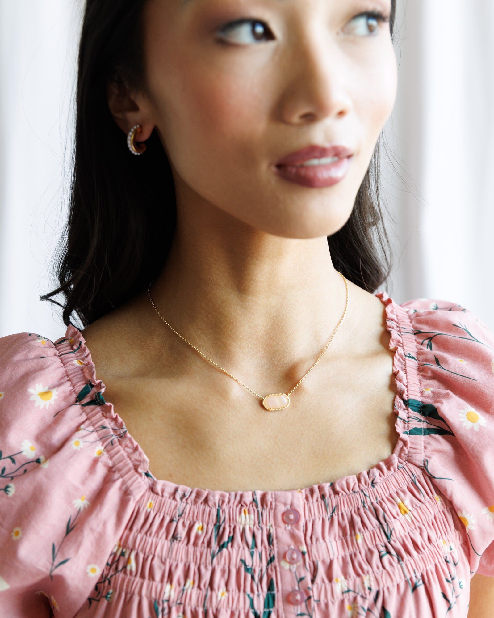 Woman wearing a pink floral dress with a delicate necklace