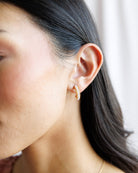 Close-up of a person wearing a gold hoop earring with a blurred background