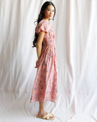 Woman wearing a pink floral dress against a white background