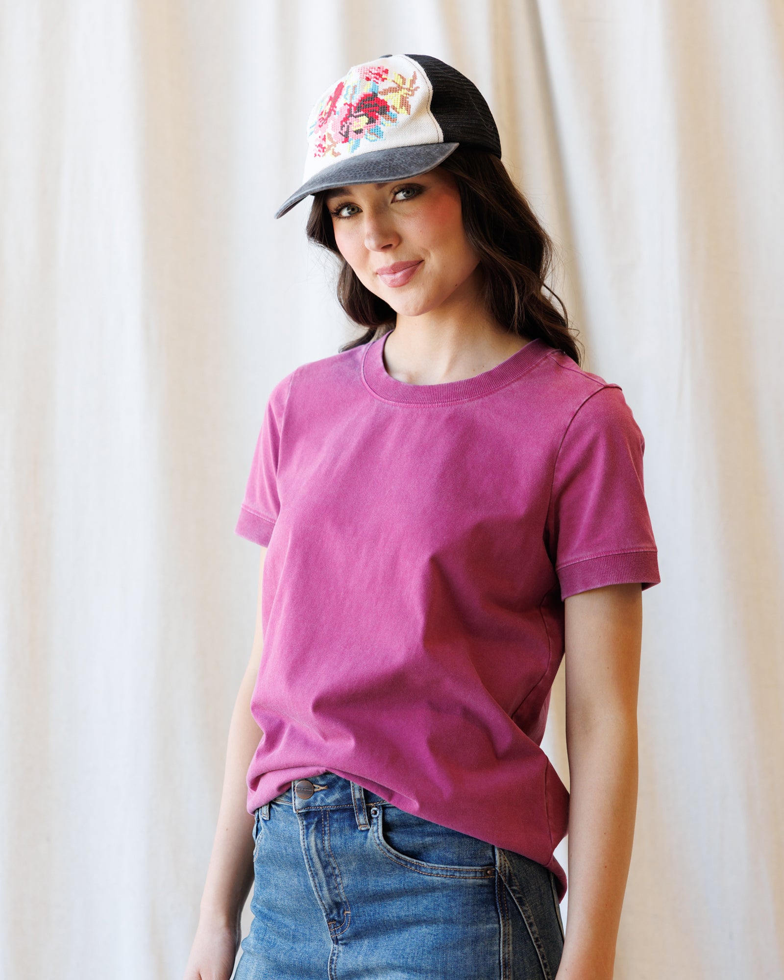 Image of woman wearing a pink short sleeve tshirt in front of a canvas backdrop