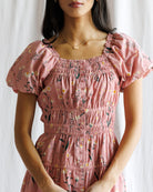 Woman wearing a pink floral dress against a white background