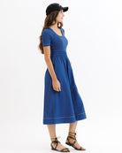 Woman wearing a blue dress and black cap on a white background