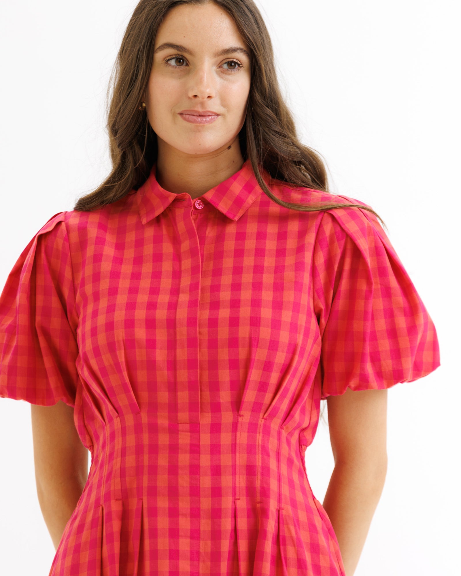 Woman wearing a red and pink checkered dress on a white background