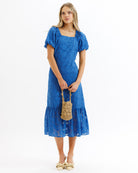 Woman wearing a blue dress holding a straw bag on a white background