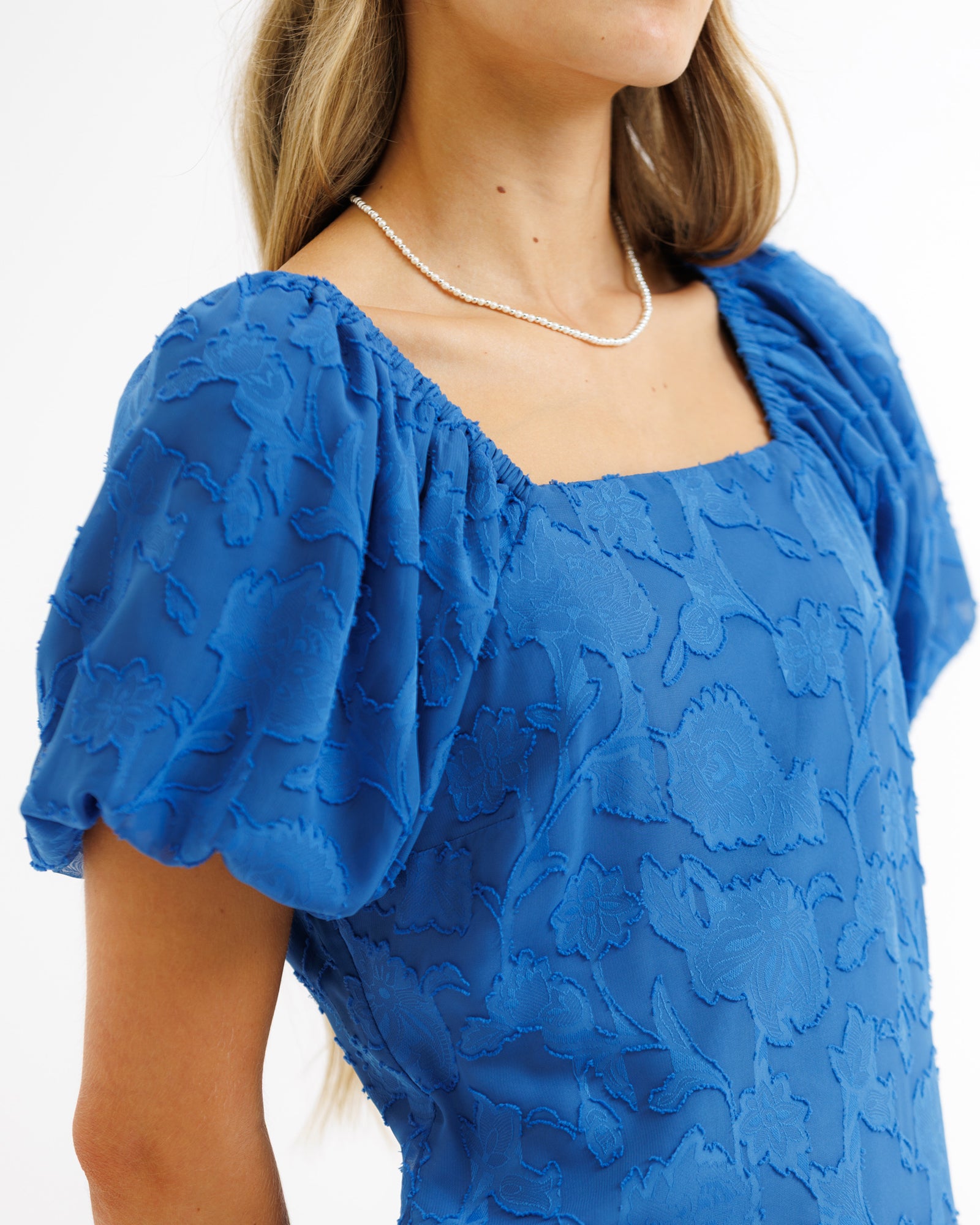 Blue lace top worn by a person on a white background