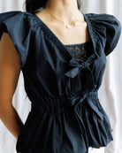 Black dress with puffed sleeves and lace detailing on a white background