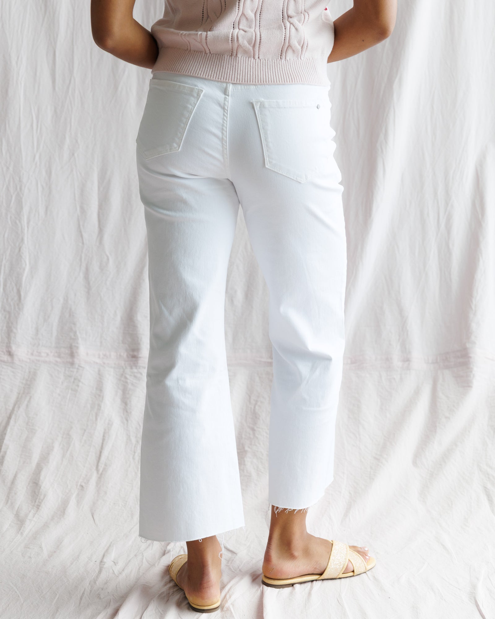 Person wearing white pants and a light pink top on a plain background