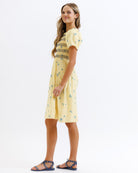 Woman wearing a yellow dress with a pattern on a white background