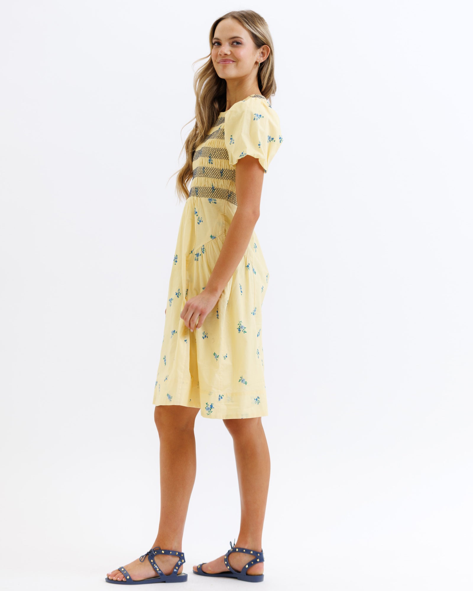 Woman wearing a yellow dress with a pattern on a white background