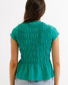 Green sleeveless top worn by a person on a white background