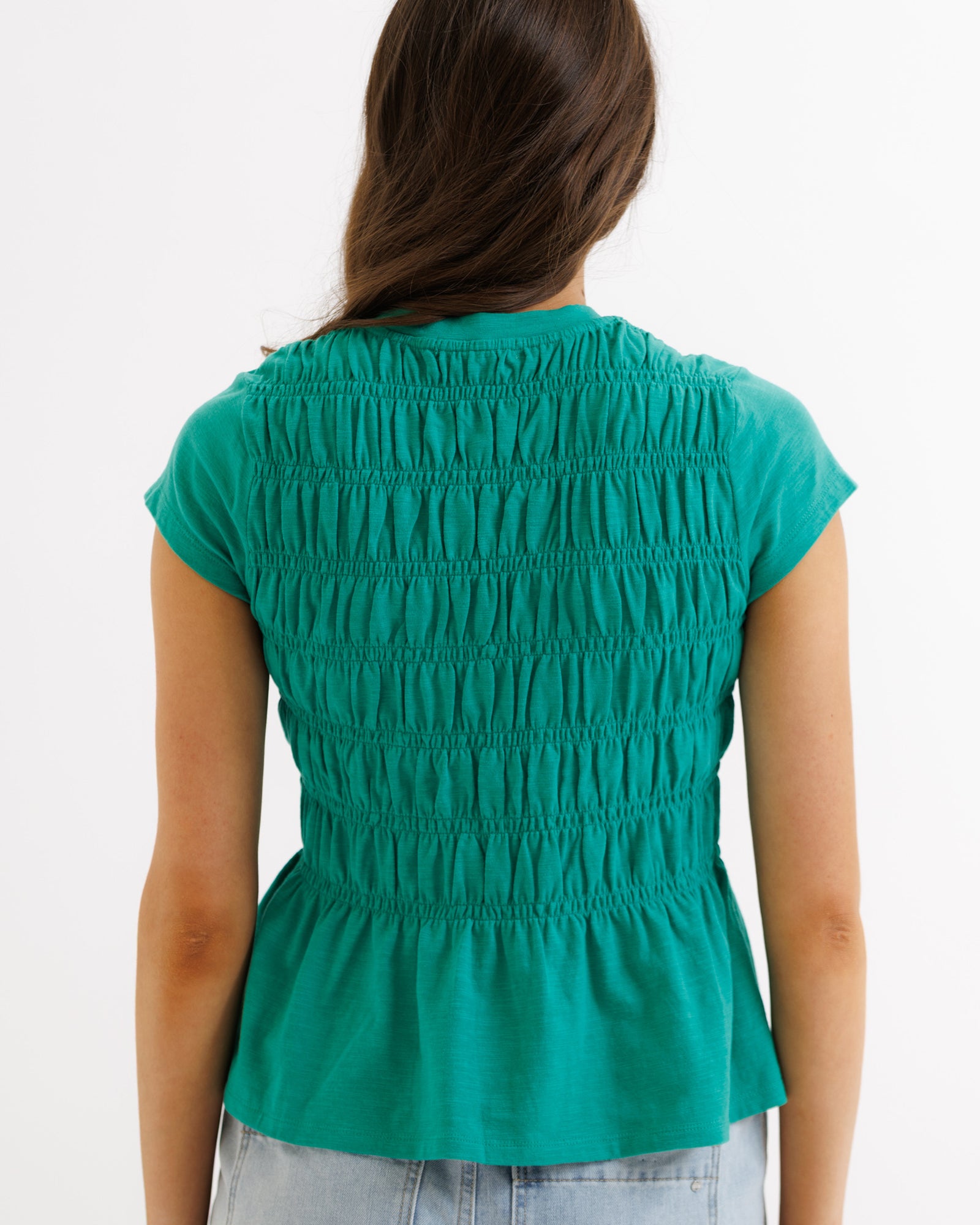 Green sleeveless top worn by a person on a white background