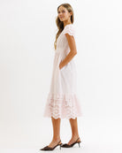 Woman wearing a pink dress with lace details on a white background