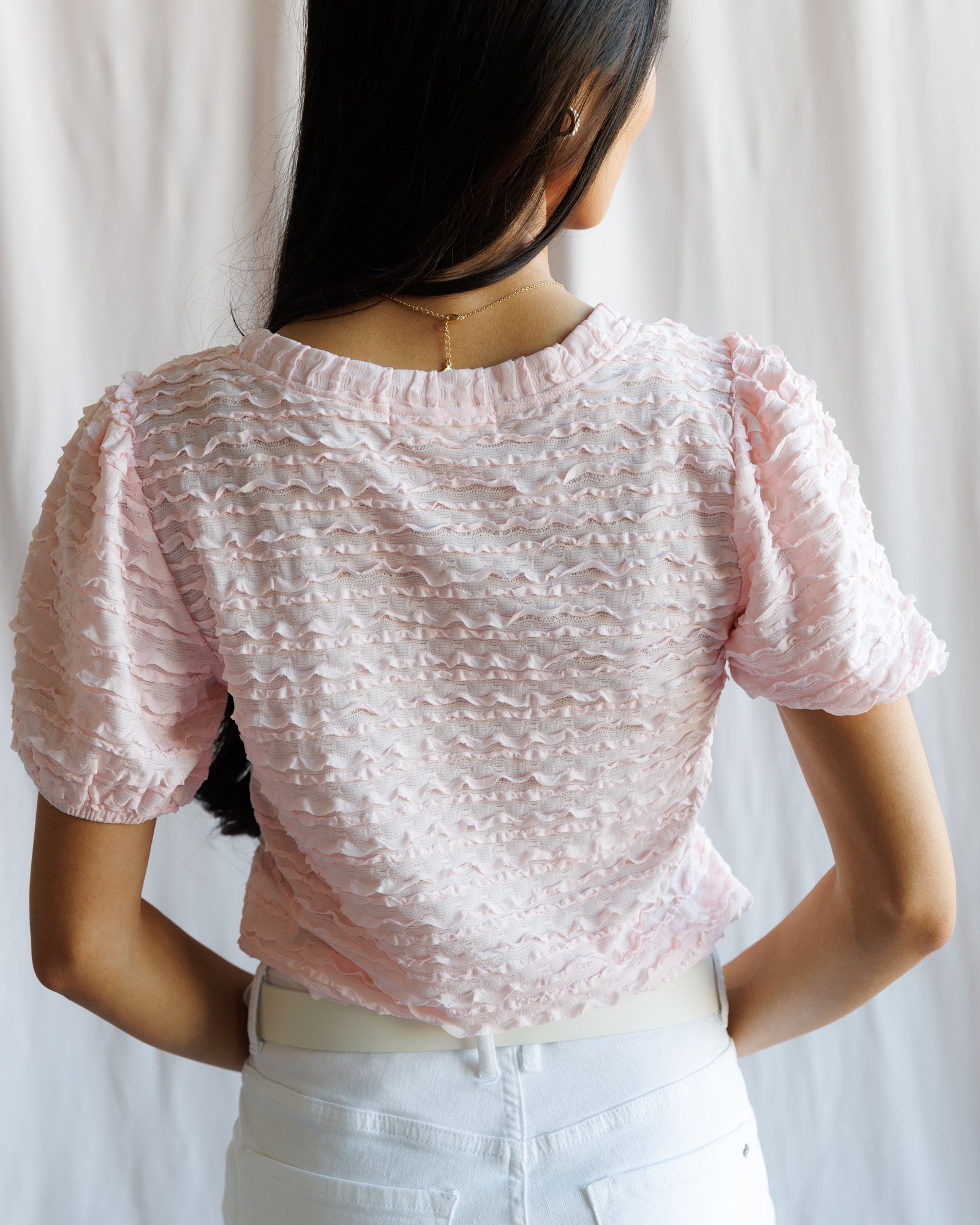Person wearing a textured pink top with a plain background