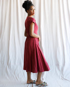 Woman wearing a red dress standing against a white curtain