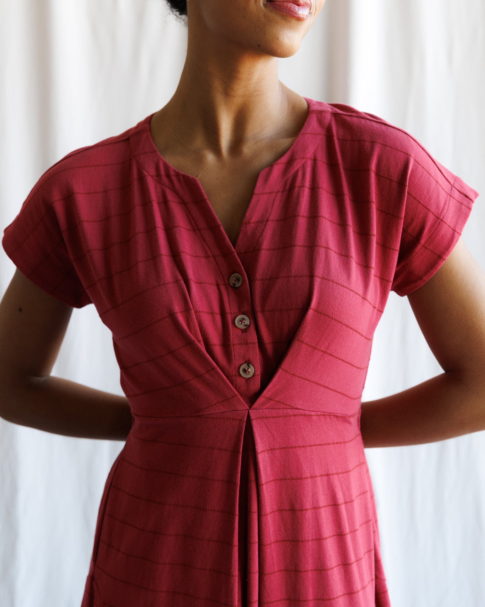 Red dress worn by a person with a white curtain background