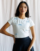 Woman wearing a white t-shirt with blue patterns against a plain background