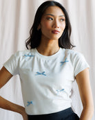 Woman wearing a white t-shirt with blue bow patterns against a plain background