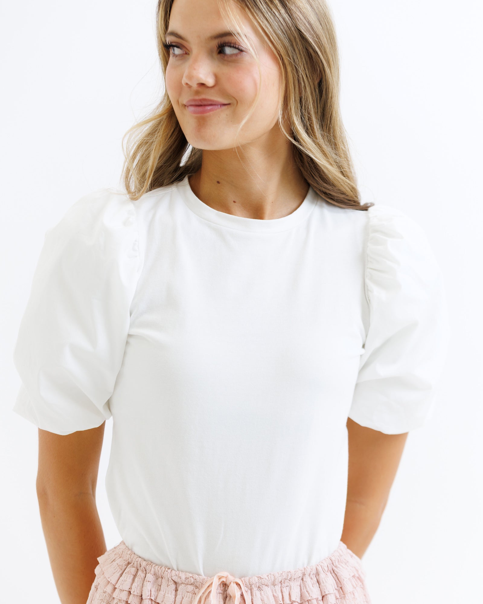 Woman wearing a white blouse with puffed sleeves on a plain background