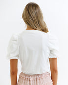 Person wearing a white blouse with puffed sleeves on a plain background