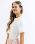 Woman wearing a white top with a plain background