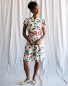 Woman wearing a floral dress standing against a white background