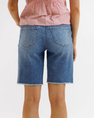 Person wearing blue denim shorts and a pink top on a white background