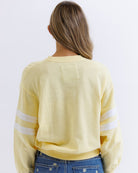 Person wearing a yellow long-sleeve shirt with white stripes on a plain background