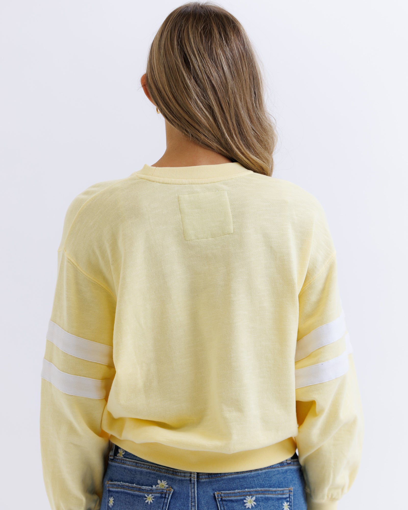 Person wearing a yellow long-sleeve shirt with white stripes on a plain background