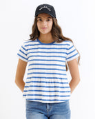 Woman wearing a blue and white striped t-shirt with a black cap on a white background