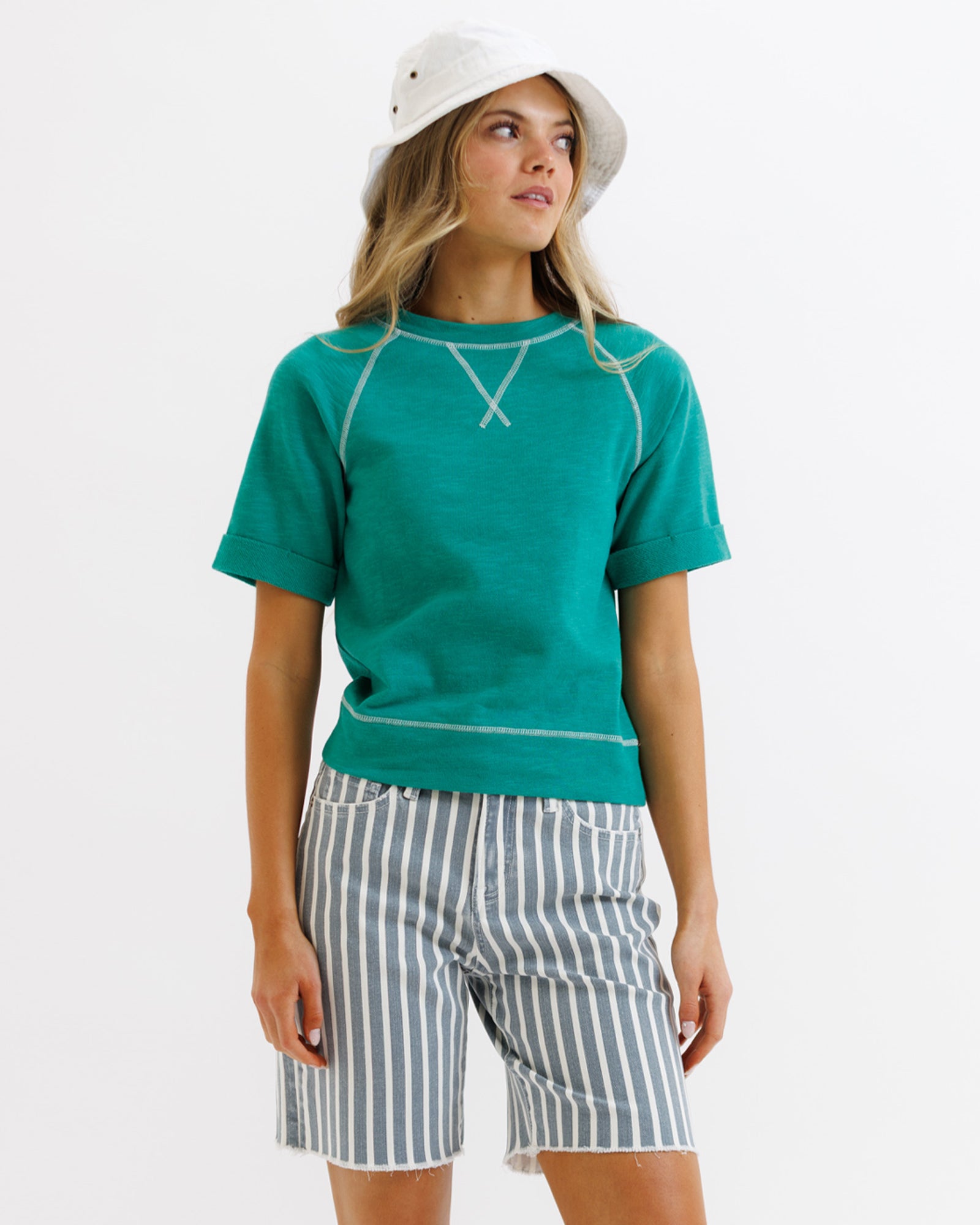 Woman wearing a teal shirt and striped shorts on a white background