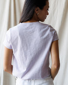 Woman wearing a light purple t-shirt against a plain background